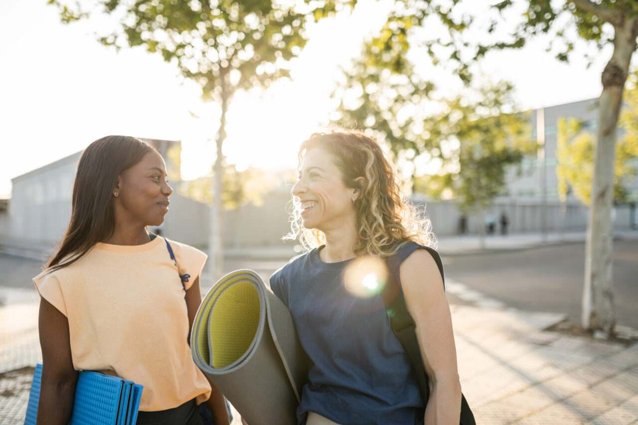 two middle-aged multiracial women go for sports together in a city park