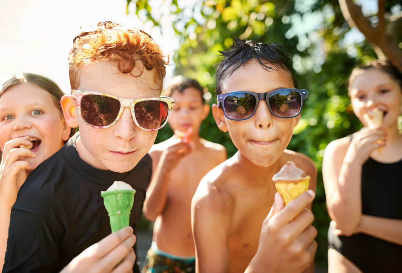 Group of cool kids while having ice cream after a swim in outdoor pool
