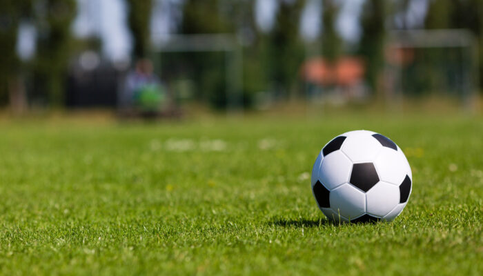 Black and white soccer ball on green soccer pitch.