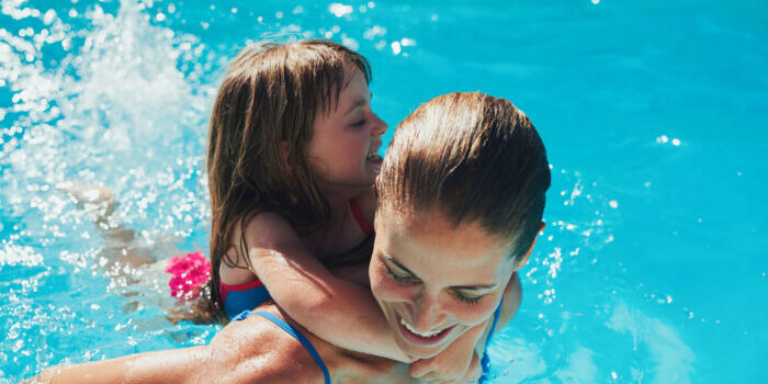 Cute little girl swimming with her mom in pool